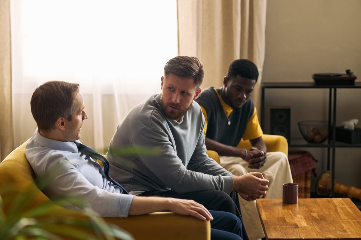Adults sitting together in a shared living room in conversation, a support meeting in a residential home